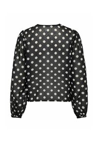 Blouse noire à manches longues avec des pois blancs, en tissu transparent, avec des poignets froncés et une coupe légèrement ample vue de dos.