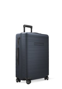 Valise rigide bleu foncé avec des rainures verticales, poignée rétractable, verrou à combinaison et quatre roues pivotantes pour plus de maniabilité.
