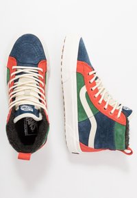 Baskets montantes avec panneaux en daim bleu, vert et rouge, accents blancs et lacets crème. Dotées d'une semelle texturée et d'un col rembourré.