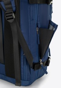 Navyblauwe rugzak met een gestructureerde stof, zwarte schouderbanden, een ritszak en meerdere compartimenten voor georganiseerde opslag.