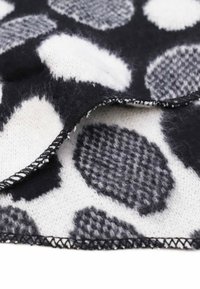 Tessuto a motivi bianco e nero caratterizzato da grandi pois con texture varie; morbida miscela di lana con un bordo cucito visibile.
