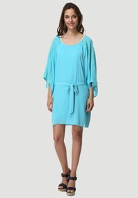 Vestido azul claro con un corte relajado, que presenta mangas sueltas de punto y un cinturón ajustable en la cintura. Detalles texturizados en el escote.