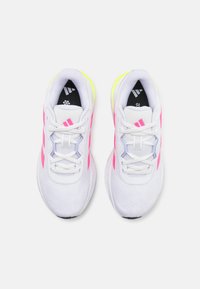 Baskets de sport blanches avec des accents roses et verts fluo, tige en maille, semelle rembourrée et lacets à l'avant, avec une languette et une semelle intérieure signées.