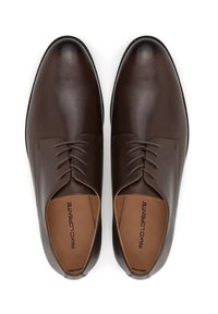 Brązowe skórzane buty eleganckie o gładkim wykończeniu, okrągłym nosku i sześciu oczkach na sznurówki. Wnętrze wkładki ozdobione jest nadrukiem logo.