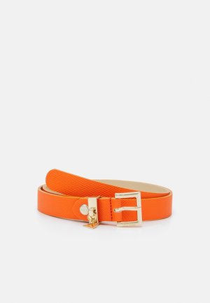 Oranje gestructureerde leren riem opgerold met een gouden rechthoekige gesp en kleine gouden hangers op een lichte achtergrond.