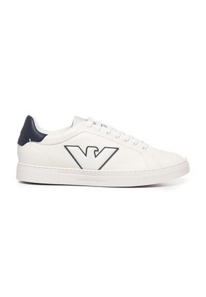 Zapatilla de cuero blanca con detalles en azul marino, punta redondeada, suela plana de goma y un logotipo prominente en el costado. Cierre con cordones y seis ojetes.