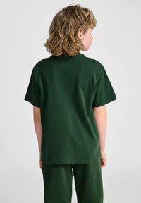 Grøn bomulds T-shirt med korte ærmer, rund halsudskæring og en afslappet pasform. Stoffet ser blødt og glat ud med en ensfarvet farve.