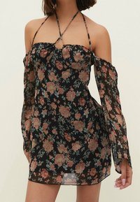 Schwarzes Kleid mit floralem Muster, schulterfreiem Design, durchsichtigen langen Ärmeln und tailliertem Oberteil. Verziert mit rosa und blauen Rosenmustern.