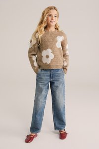Brown sweater with white flower patterns, paired with light blue, loose-fitting jeans and red flats. The texture appears soft and cozy.