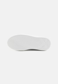 White sneaker sole with a textured wave pattern and a logo on the side, featuring a rounded shape and smooth finish.