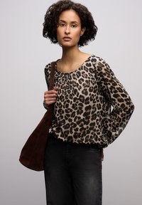 Beżowo-brązowa bluzka w panterkę, lekka tkanina, okrągły dekolt, długie rękawy, zestawiona z ciemnymi jeansami i brązową torebką na ramię.