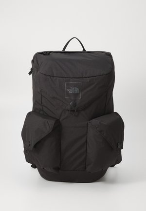 Zaino nero North Face con manico superiore, chiusure a patta sulle tasche frontali e laterali, e dettaglio centrale con bottone a pressione.