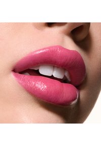 Fulde, glansende læber i en livlig pink nuancer med en glat tekstur, der afslører hvide tænder. Nærbillede af den nederste halvdel af ansigtet.