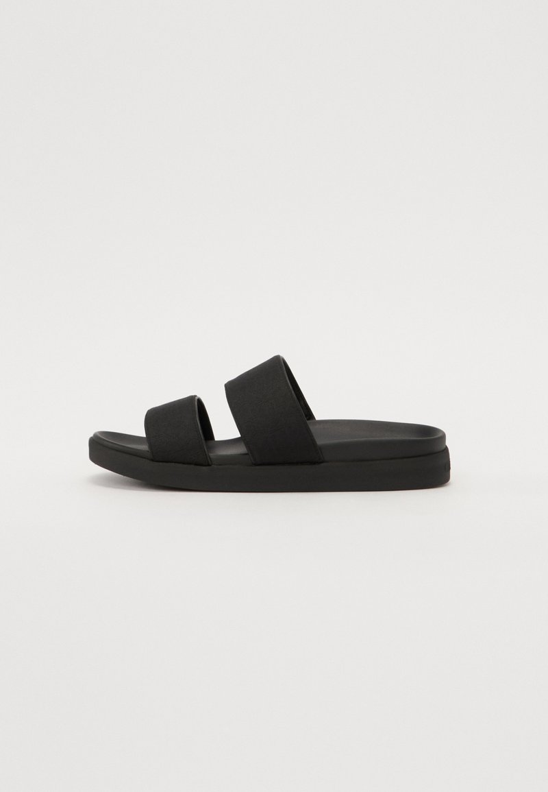 Black slide sandals featuring two adjustable fabric straps, a textured upper, and a thick rubber outsole for comfort and support.