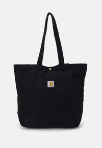Zwarte canvas tote bag met twee lange handvatten, een voorvak en een cirkelvormig logo. Voorzien van een drukknoopsluiting aan de bovenkant.
