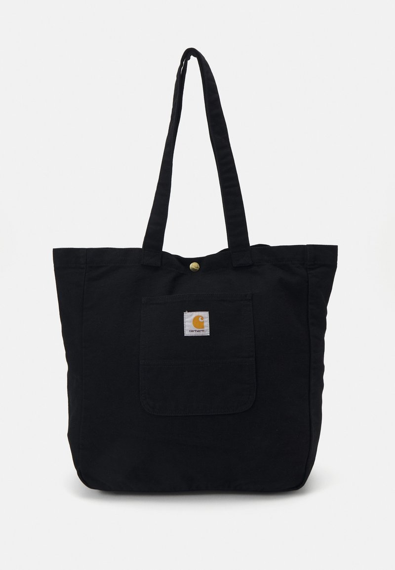 Zwarte canvas tote bag met twee lange handvatten, een voorvak en een cirkelvormig logo. Voorzien van een drukknoopsluiting aan de bovenkant.