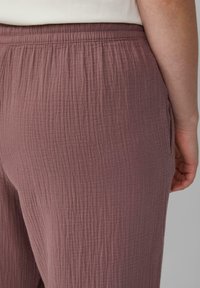 Gestructureerde, mauve broek met een elastische tailleband, voorzien van een ontspannen pasvorm en zijzakken, die de gekreukte stofontwerp benadrukt.