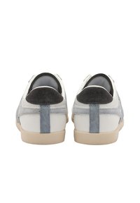 Baskets avec un corps en cuir blanc, des accents en daim gris et un onglet de talon gris foncé contrastant, présentant une semelle texturée de couleur crème.