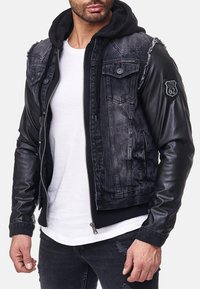 Zwarte denim en leren jack met een capuchon, twee borstzakken, versleten schouderdetails en een patchaccent op de mouw.