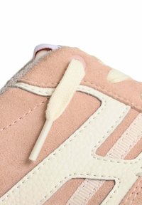 Scarpa sportiva di colore rosa chiaro con tomaia in suede, dettagli bianchi testurizzati e sistema di allacciatura flessibile. Caratterizzata dai materiali e dai colori a contrasto.