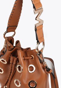 Brown leather bucket bag featuring gold hardware, woven accents, and round eyelets. Includes a thick, patterned shoulder strap.