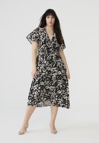 Abito nero a fiori con maniche a sbuffo corte, scollatura a V e gonna fluida. Presenta motivi floreali bianchi e una vita arricciata per un fitting perfetto.