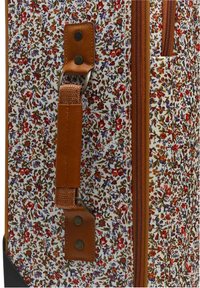 Valigia floreale su sfondo bianco, con fiori multicolori. Dettagli in pelle marrone, un manico textured e chiusura con zip.