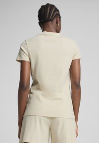 Lichtbeige ribbeltrui met korte mouwen en een ronde halslijn, gecombineerd met bijpassende shorts. De stof heeft een zachte textuur en een aansluitende pasvorm.