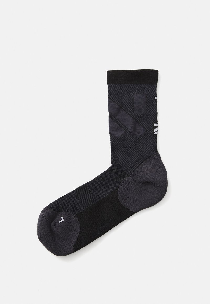 Calcetín deportivo negro con un diseño texturizado que presenta varios patrones de punto, puntera sólida y un acento de logo en blanco.
