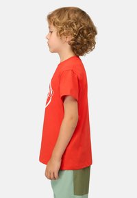 Roter Baumwoll-T-Shirt mit kurzen Ärmeln und Rundhalsausschnitt, das ein weißes Grafikdesign zeigt, kombiniert mit hellgrünen Shorts und einem Patches-Detail.