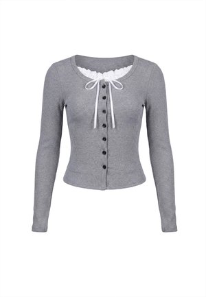Harmaa ribbineuloksinen pitkähiha cardigan, jossa mustat napit edessä ja valkoinen pitsireunus sekä rusetti pyöreässä pääntiessä.