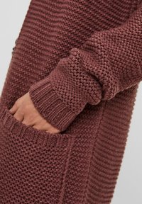 Sweter na guziki w kolorze burgundowym, wykonany z fakturowanej dzianiny z wzorem diamentu, z prążkowanymi mankietami i boczną kieszenią.