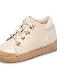 Scarpa beige per bambino con pelle lucida, bordi decorativi a scallop, dettaglio a fiore vicino ai lacci e suola in gomma.