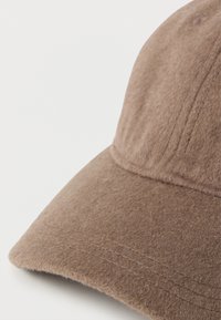 Pruun villane kork pehmea tekstuuriga, kumerate servade ja õmmeldud detailidega. Omab ümarat kroon, mis tagab sobiva istuvuse.