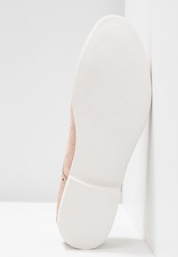 Semelle d'une chaussure en daim rose clair avec une semelle en caoutchouc blanc montrant de fines lignes d'adhérence horizontales et un talon texturé, taille 37 marquée.