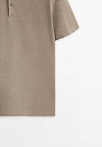 Polo à manches courtes en tissu tissé léger marron clair avec un col, comportant une patte de boutonnage à deux boutons et une texture lisse.