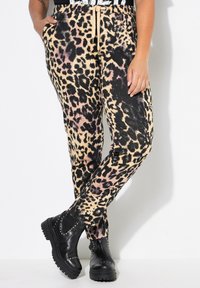 Pantalones de chándal con estampado de leopardo hechos de una tela suave, con una cinturilla elástica con cordón y bolsillos, combinados con botas de plataforma negras.