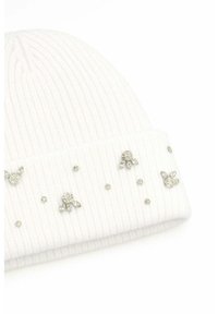 Berretto bianco a costine in maglia con risvolto decorato da piccole e medie applicazioni di pietre preziose trasparenti disposte a motivi floreali.