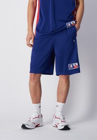 Pantalones cortos deportivos de la Marina con acentos rojos en los laterales, fabricados con una tela ligera. Presenta un parche con el logo y una cinturilla elástica para mayor comodidad.
