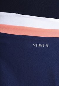 Tela de color marino con rayas horizontales en blanco y rosa. Etiqueta "CLIMALITE" en texto pequeño y blanco. Textura suave y diseño atlético.