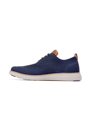 Sneaker a maglia blu navy con una superficie liscia, suola intermedia bianca e dettagli in pelle marrone nel tallone e nella linguetta. Presenta un design traspirante.