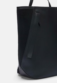 Czarna torba na ramię z teksturowaną siateczką z boku, gładkimi skórzanymi akcentami, usztywnionym kształtem i podwójnymi uchwytami ułatwiającymi noszenie.