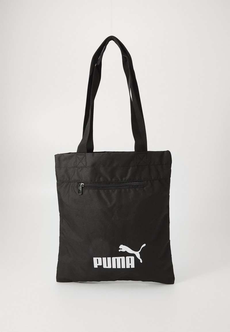 Melnas tote somiņas izgatavotas no izturīga auduma, ar augšējo rāvējslēdzēju, divām plecu siksnām un baltu Puma logo priekšā.