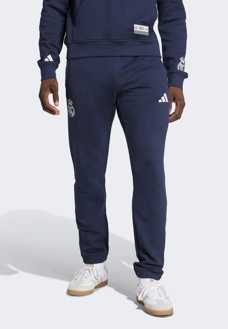 Mornarskoplav sweatshirt Adidas i odgovarajući dukserice. Sweatshirt ima logotip s prednje strane, a dukserice imaju logotip na butini i bočne pruge.