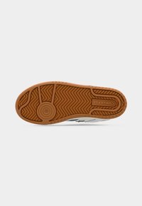 Πάτος ενός αθλητικού παπουτσιού με καφέ ελαστικό πέλμα, κυκλικά και ζιγκ-ζαγκ σχέδια και λογότυπο "CONVERSE" χαραγμένο κοντά στη φτέρνα.