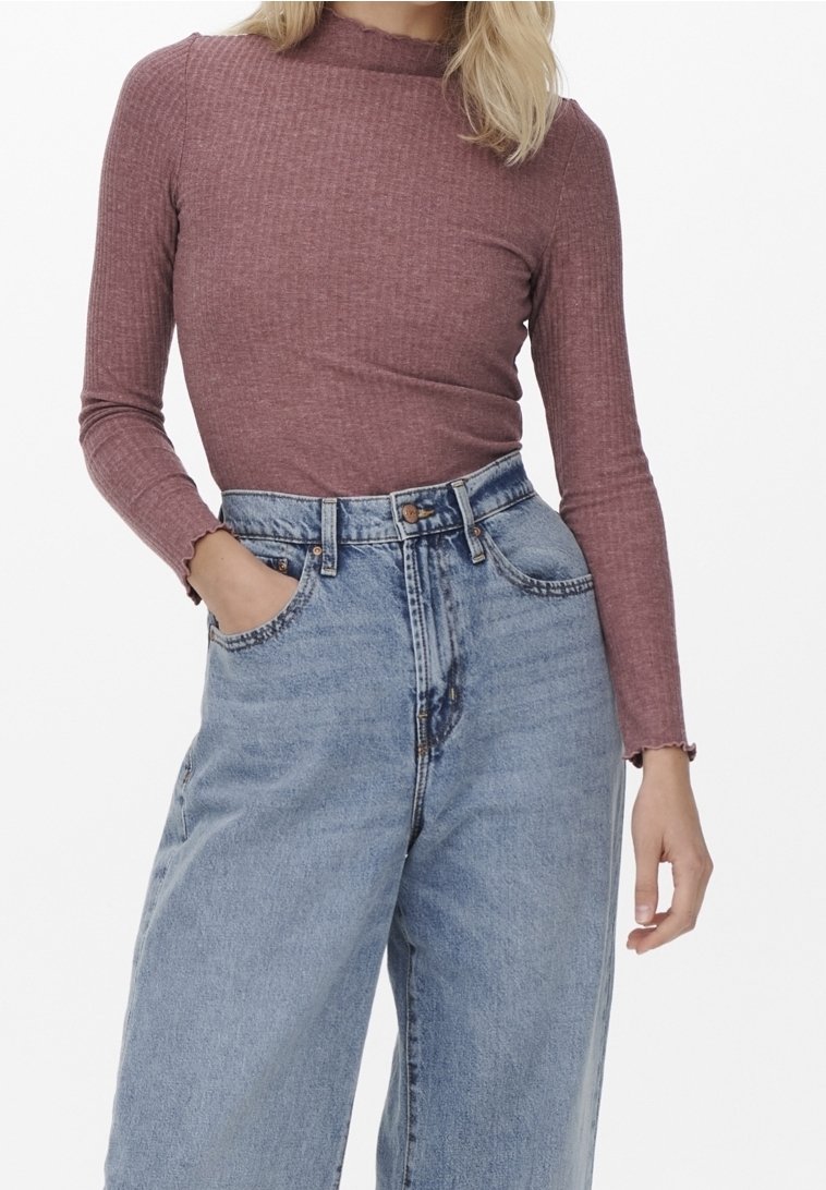 Langärmliges, geripptes Oberteil in sanftem Mauve mit hohem Kragen, kombiniert mit hochgeschnittenen, hellblauen, weit geschnittenen Jeans mit fransigem Saum.