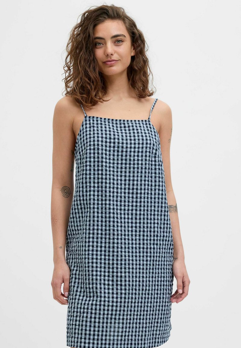 Vestido de cuadros azul y blanco con tirantes finos, silueta recta y tejido ligero. Sin patrones ni elementos metálicos visibles.