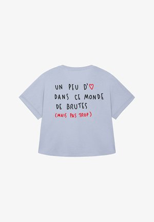Világoskék, bő szabású póló, hátulján nyomtatott szöveggel: "Egy kis szeretet ebben a brutális világban (de ne túl sok)" és egy piros szív szimbólummal.