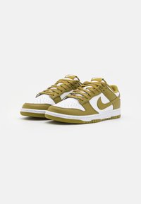 Un paio di sneakers low-top Nike bianche e verde oliva con lacci, punta perforata e logo swoosh, mostrato su sfondo bianco.