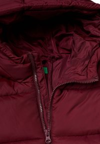 Bordowa kurtka puchowa z zamkiem błyskawicznym z przodu, charakteryzująca się gładką, błyszczącą teksturą i małą zieloną metką wewnątrz kołnierza.